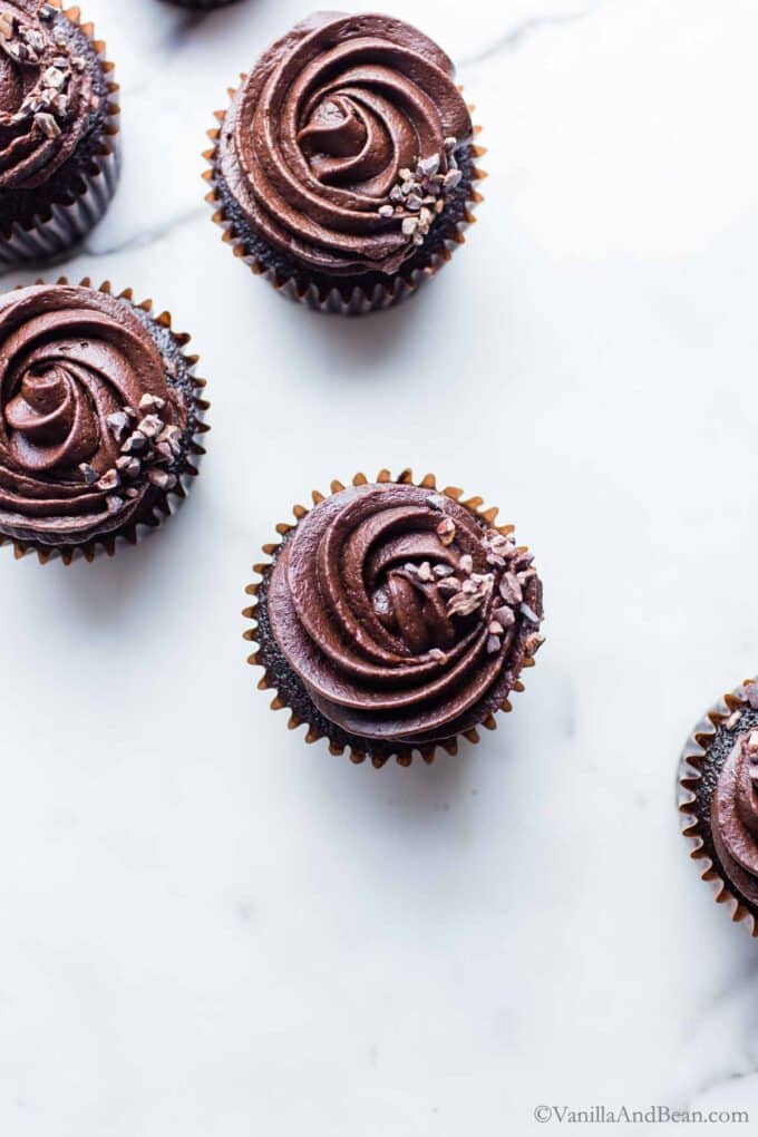 Dark Chocolate Cupcakes with dark chocolate butter cream on a marble table.