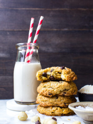 Coconut and Macadamia Nut Cookies stacked on top of each other next to a glass of milk.