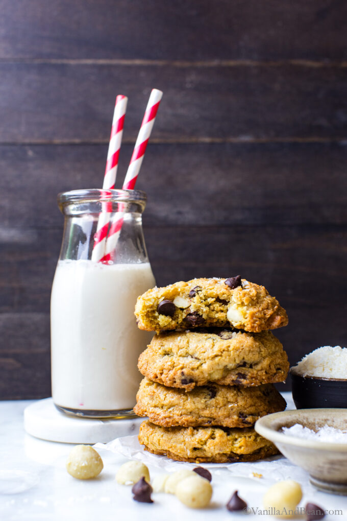 Coconut and Macadamia Nut Cookies stacked on top of each other next to a glass of milk.