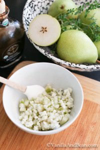 Chopped blue cheese and diced pear mixed in a small bowl with spatula
