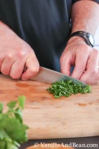 Fresh cilantro chopped with a knife on a chopping board