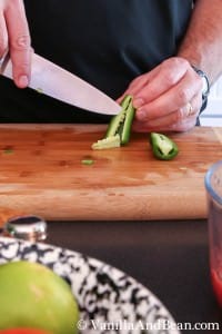 Removing seeds from a jalapeño pepper with a knife on a chopping board
