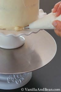 An open star tip and a pastry piping bag with a shell border on the base of the cake