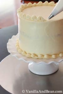 An open star tip and a pastry piping bag lining the top of the cake with a shell border