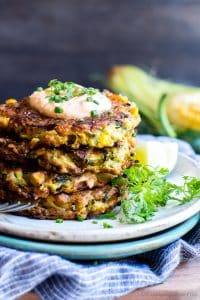 Corn and Zucchini Fritters stacked tall on a plate.