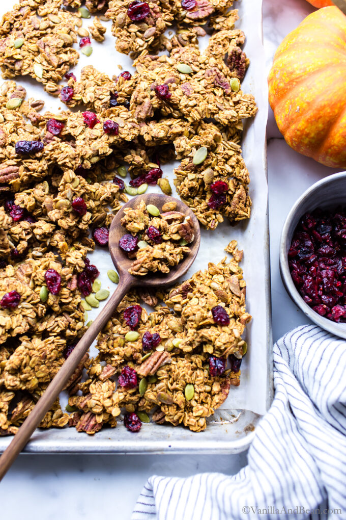 Baked crunchy pumpkin granola in a pan with a spoon holding some granola.