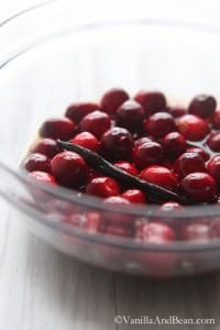 Fresh cranberries in a glass bowl mixed with bourbon, star anise, brown sugar and vanilla bean.