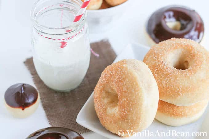 Baked doughnuts topped with ganache on a plate and doughnut holes in a small bowl
