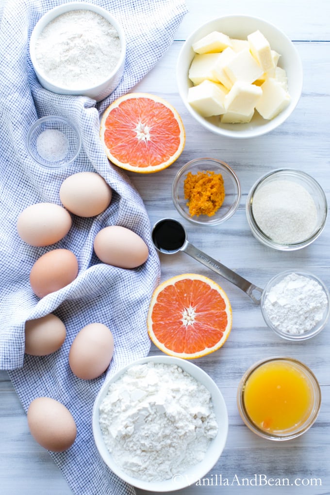Eggs, orange sliced in half and other ingredients in separate bowls for the Orange Crumble Tart.