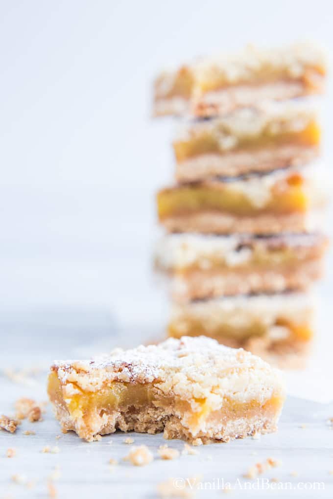 An Orange Crumble Tart with a bite and a stack of tarts behind it.