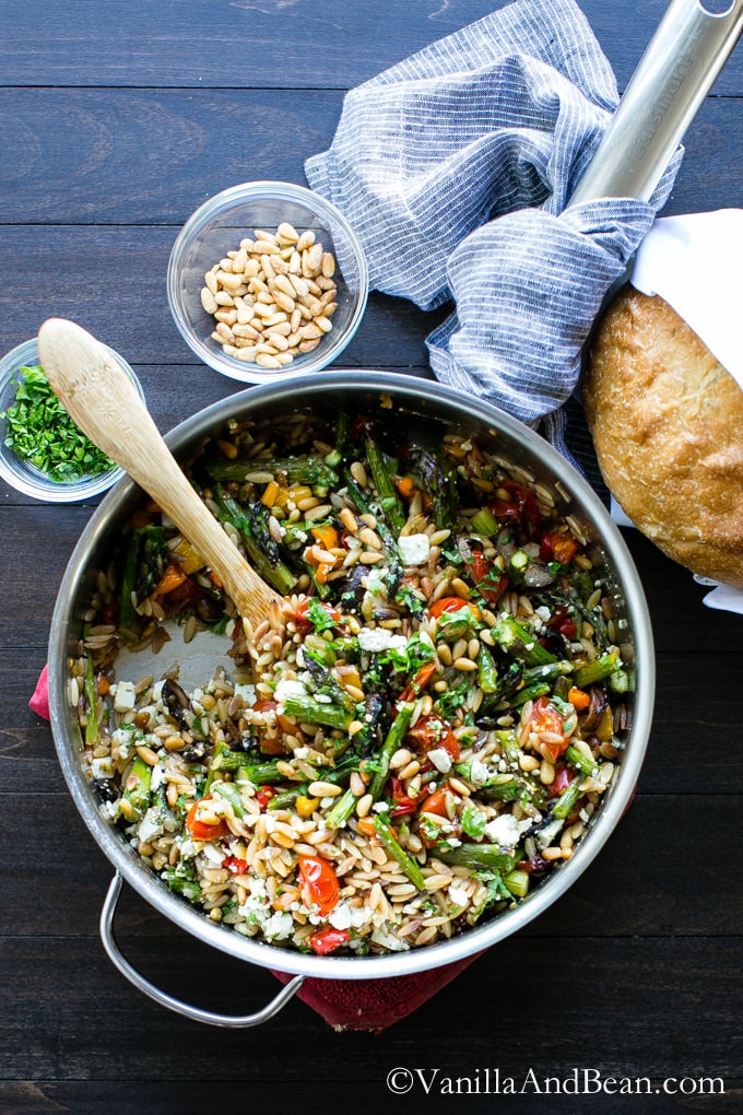 Lemon Garlic Orzo with Roasted Vegetables in a skillet with bread and pine nuts on the side. 