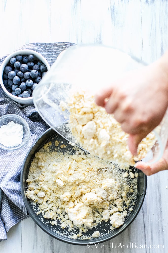 Transferring the crumbly mixture to a spring form nonstick pan.