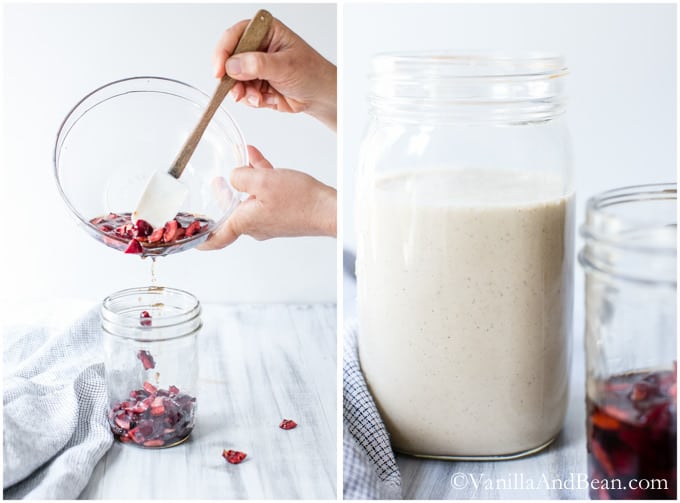 A bowl of cherries poured into a mason jar beside another mason jar containing coconut milk.
