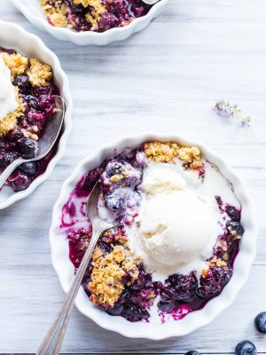 Blueberry Cornmeal Crisp in individual serving dishes with ice cream on top.
