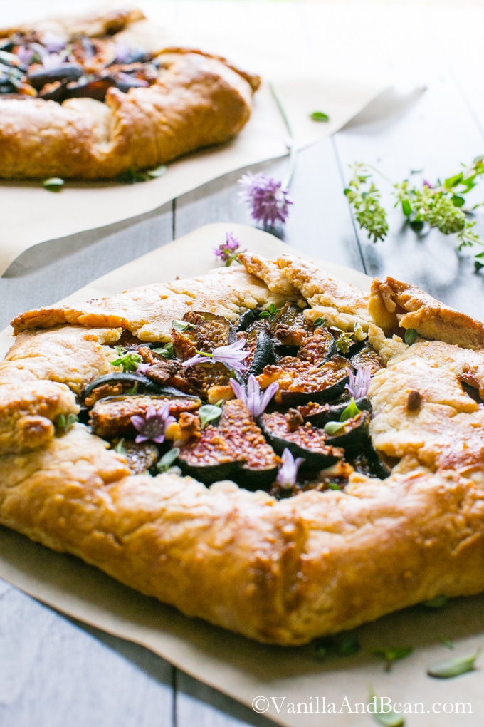 Caramelized Onion and Fig Galette with Goat Cheese and Herbs on a wood board ready for sharing. 