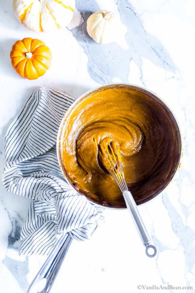 Homemade pumpkin butter in a pan with a whisk. It thickens as it cools.