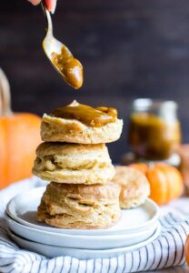 Slathering delicious pumpkin butter on the biscuit tower served in a white plate