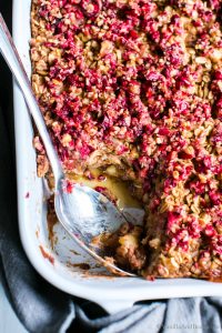 Apple Baked Oats with Cranberry Crumble in a pan with a spoon.