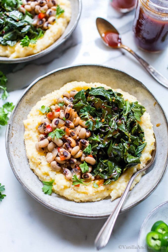 Collard greens and black eyed peas with grits in a bowl with a spoon.