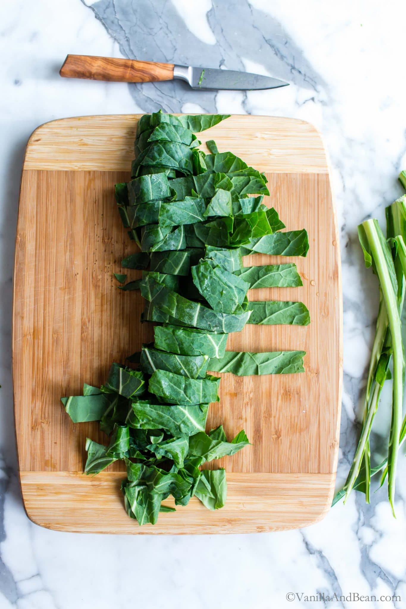 Cutting the collard greens into ribbons on a cutting board.