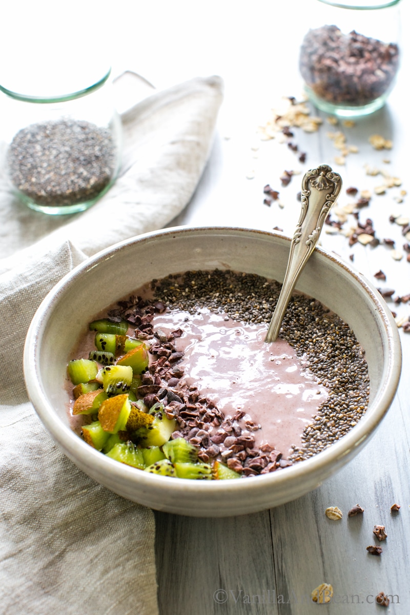 Cherry Almond Smoothie Bowl topped with kiwi, chia seeds and cocoa nibs ready for sharing.