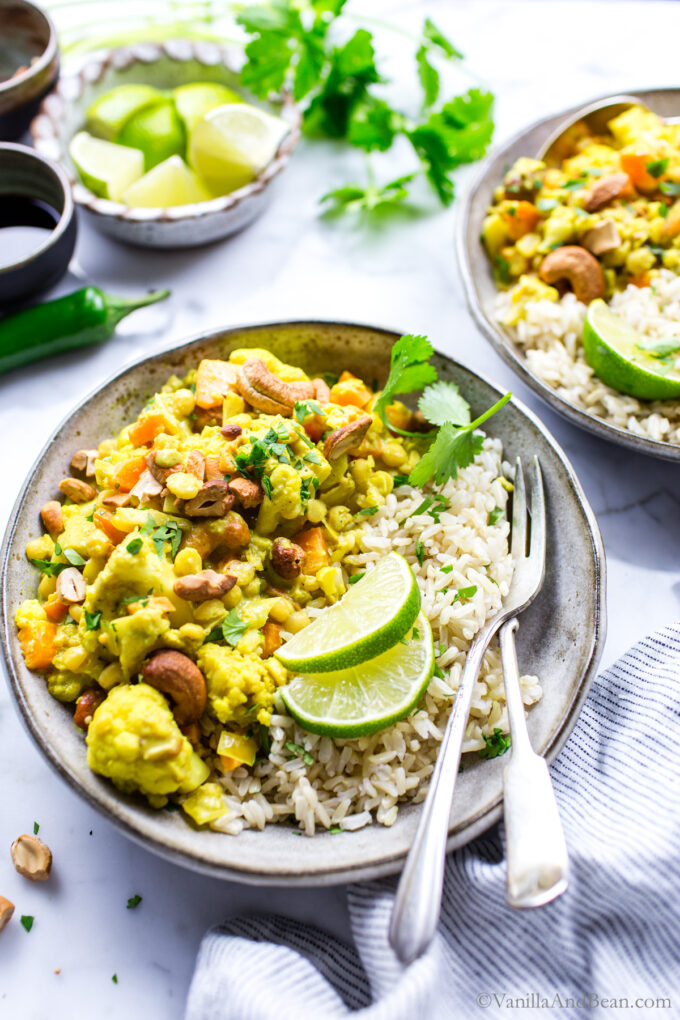Chana Dal Recipe with cauliflower, cashew and coconut milk in a serving bowl with rice and garnished with limes.