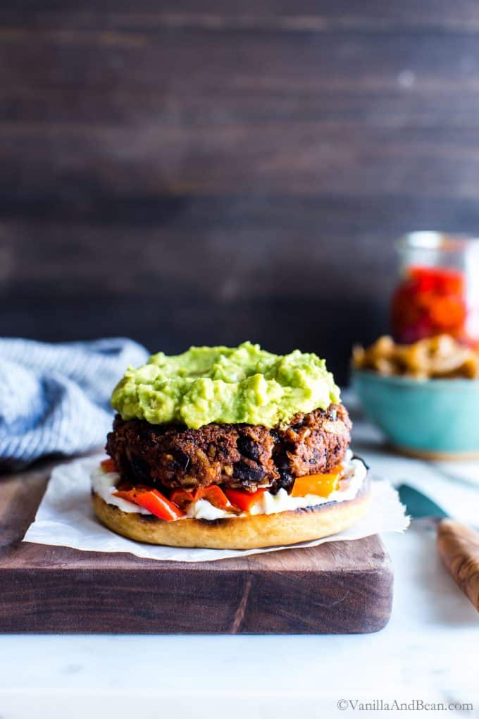 Black bean burgers on a board topped with guacamole.