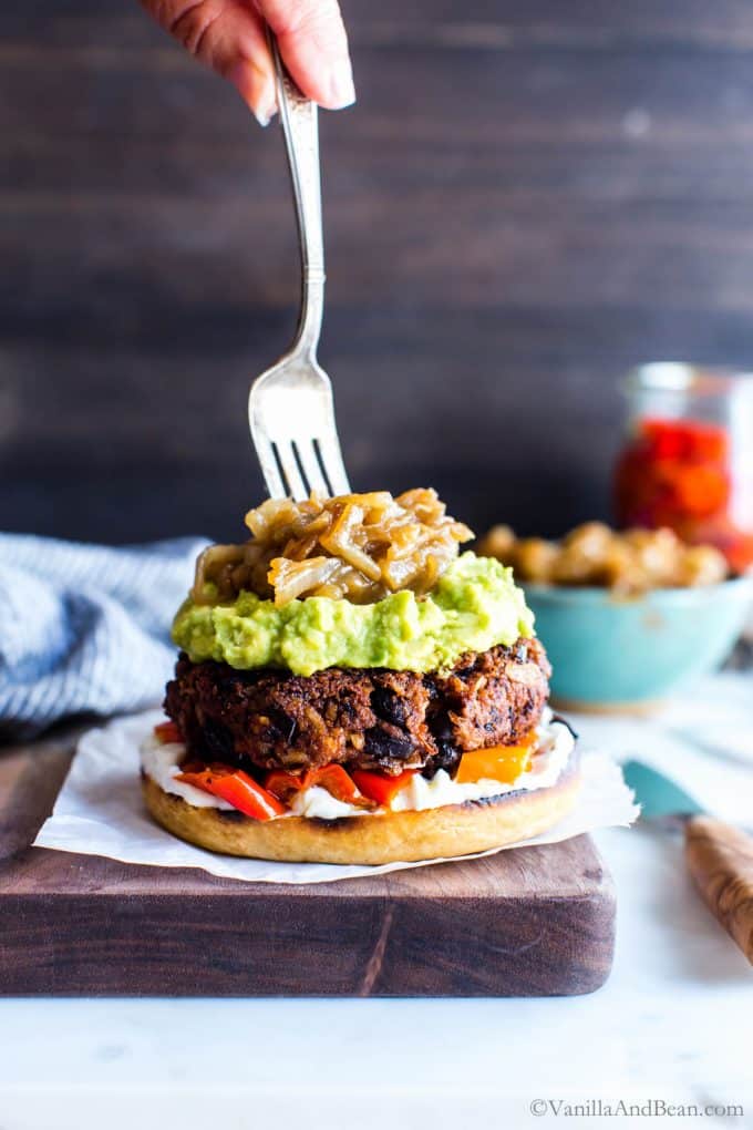 A fork topping Black bean burgers with saucy onions.
