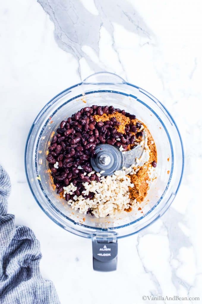 Black beans, rice and spices in a food processor bowl.