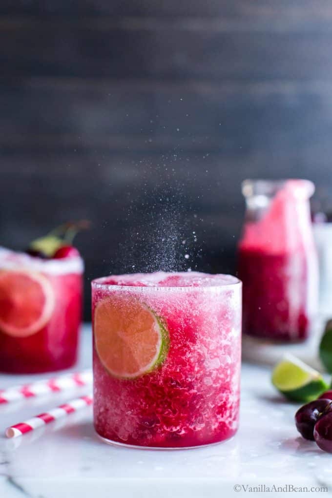 Fizzy cherry limeade in a glass garnished with lime.
