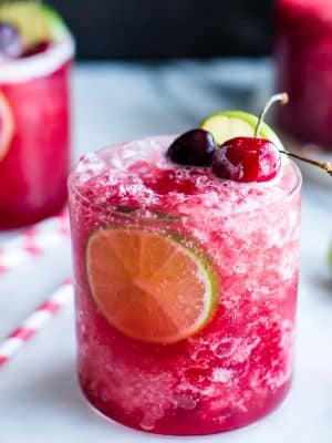 Closeup of cherry Limeade garnished with lime and cherries.