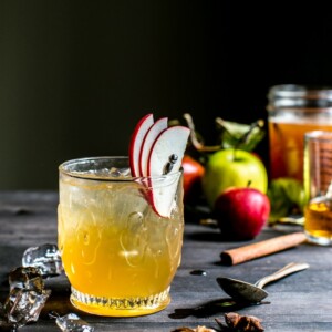 Bourbon Apple Cider Shrub Cocktail in a glass garnished with apple slices.