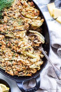 White bean mushroom and roasted fennel gratin, vegetarian in a pan with a spoon scooping a portion out.