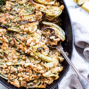 White bean mushroom and roasted fennel gratin, vegetarian in a pan with a spoon scooping a portion out.
