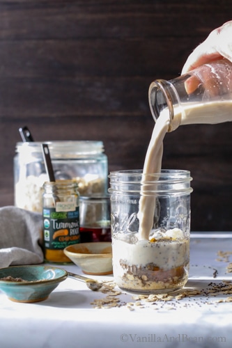 Pouring milk into a jar with the ingredients for overnight Turmeric Chia Oats