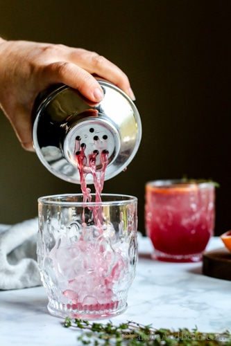 Pouring the cocktail in an ice filled glass. 
