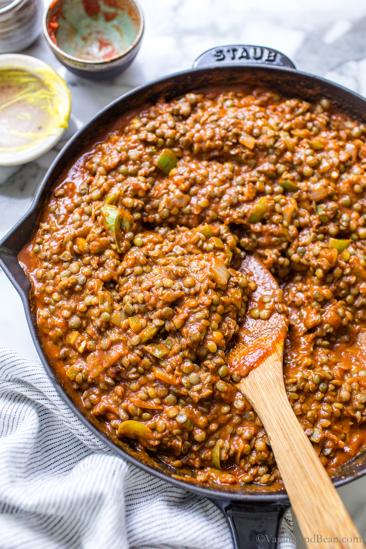 Lentil sloppy joes in a skillet with a wood spoon.