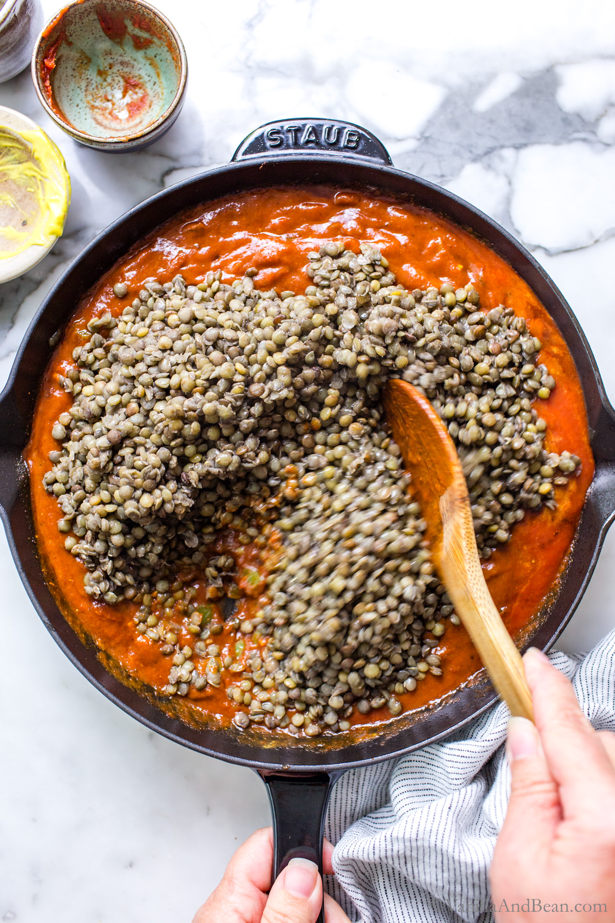 Lentil sloppy joes in a skillet with a wood spoon.