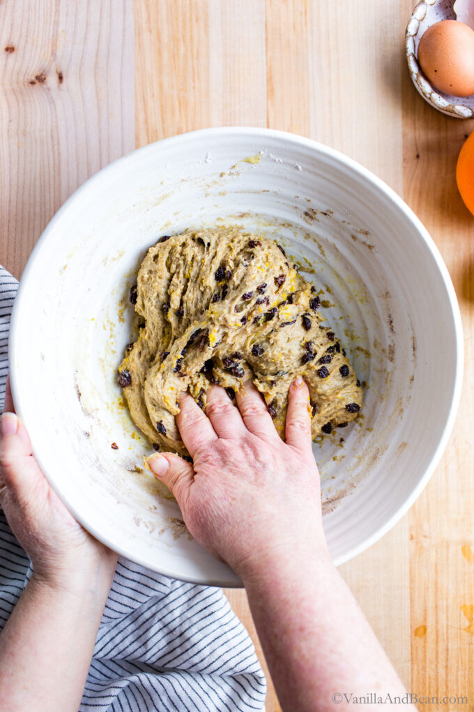 Hot cross bun dough is mixed by hand in a bowl.