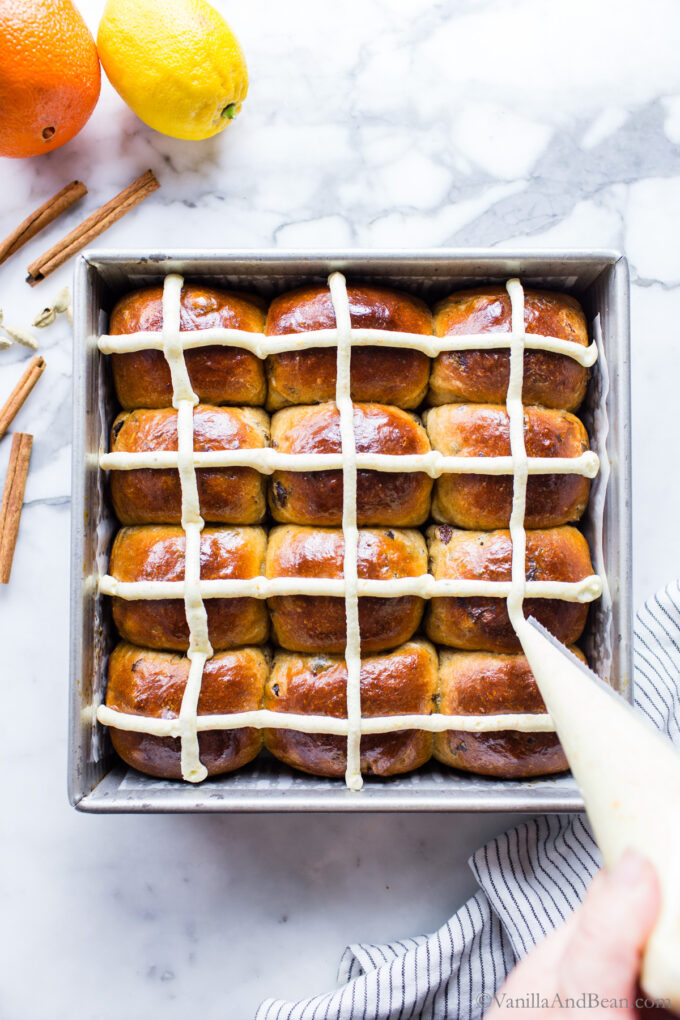 Icing being piped over cooled hot cross buns.