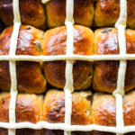 Close up of soft hot cross buns with vanilla mascarpone icing cross on top.