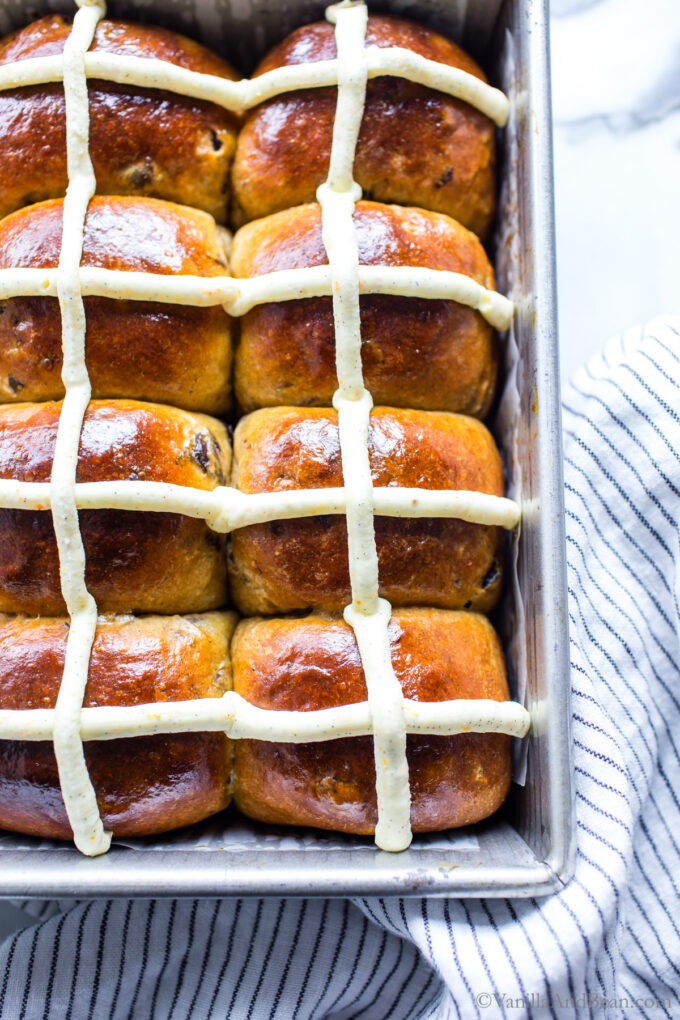 Soft Hot cross buns in a pan with a mascarpone icing cross on top.