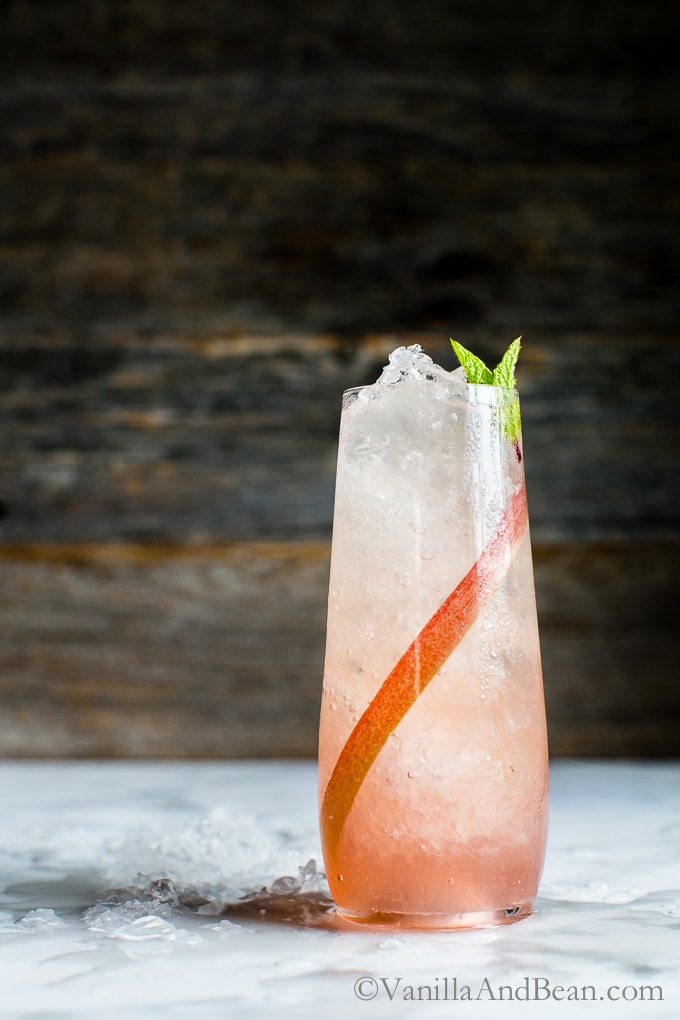 Iced, lemongrass-Ginger Rhubarb Soda in a champagne flute garnished with mint. 