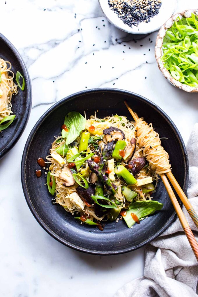 Asparagus mushrooms and bok choy noodles in a black serving bowl with chop sticks. 