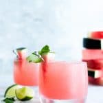 Watermelon Mojitos in ice filled glasses garnished with a watermelon wedge.