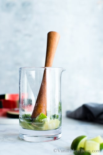 Muddling lime, mint and simple in a cocktail mixer glass. 