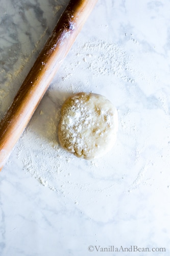 A pastry round with a wood rolling pin covered in flour. 