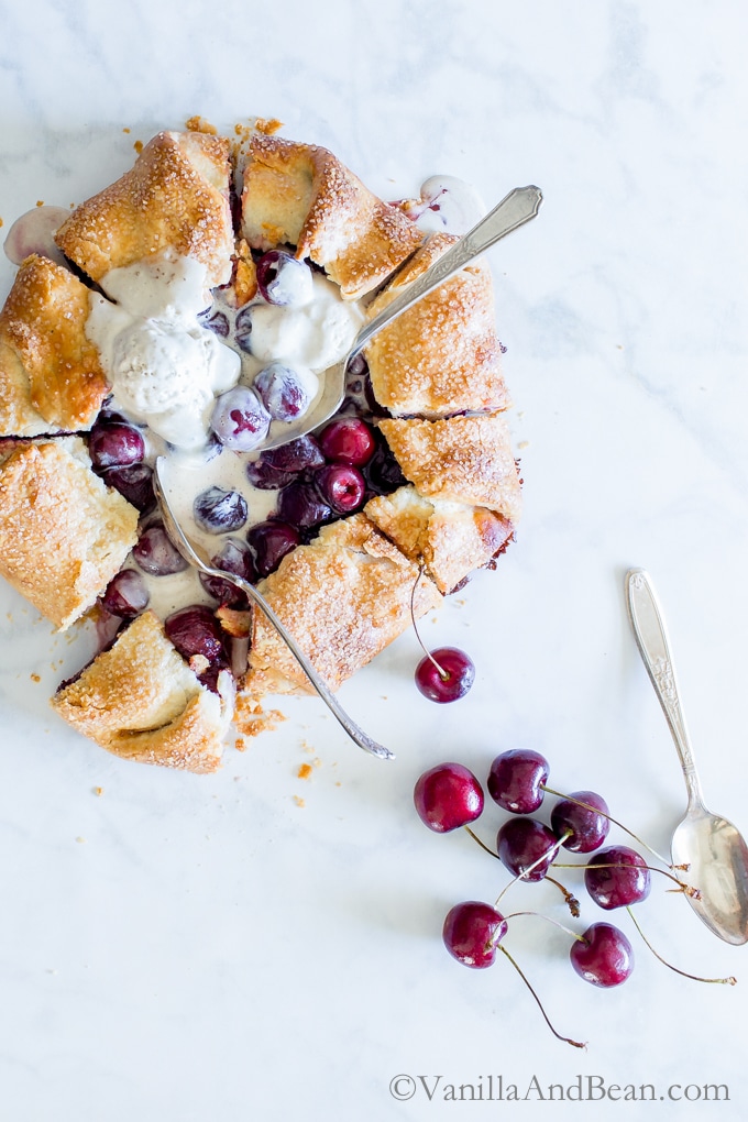 Sweet Cherry Galette topped with ice cream and several spoons digging in. 