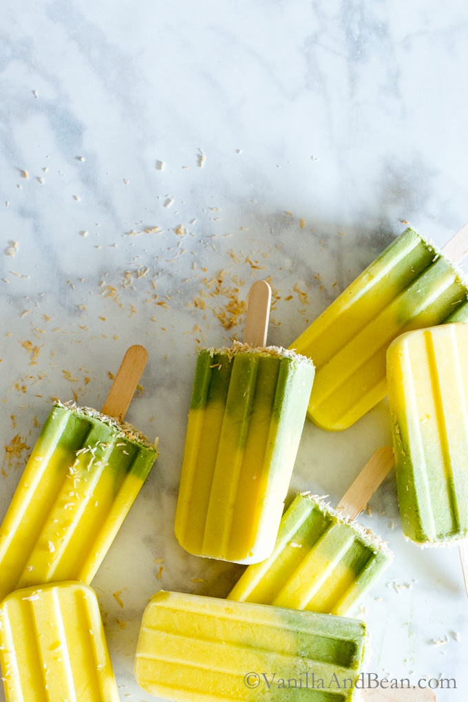 Matcha-Mango Coconut Popsicles on a marble counter.