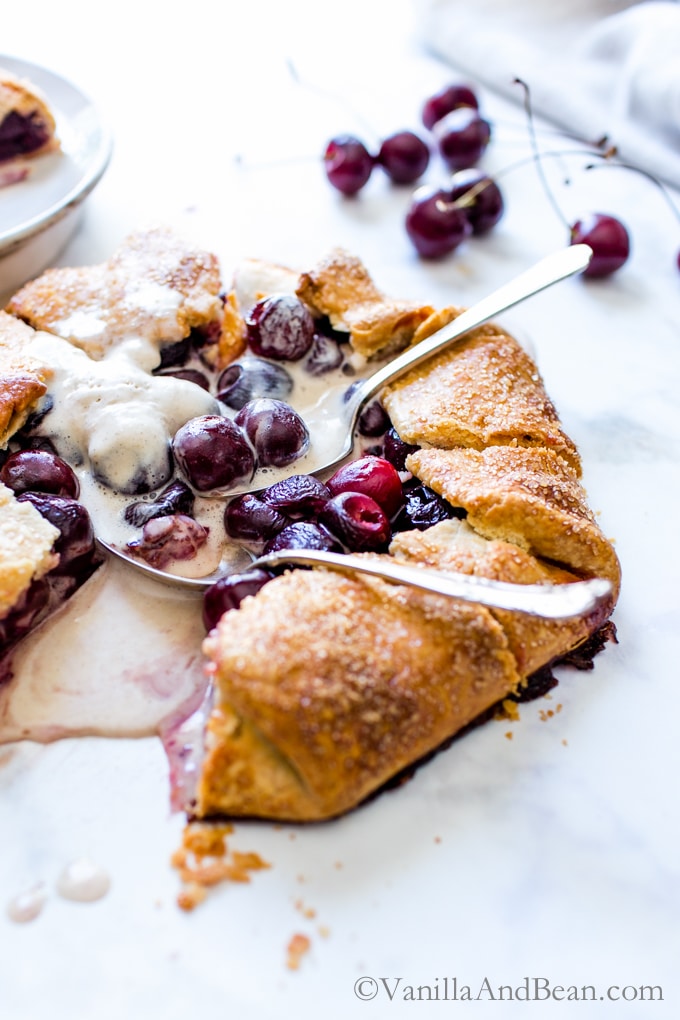 Sweet Cherry Galette topped with ice cream and several spoons digging in.